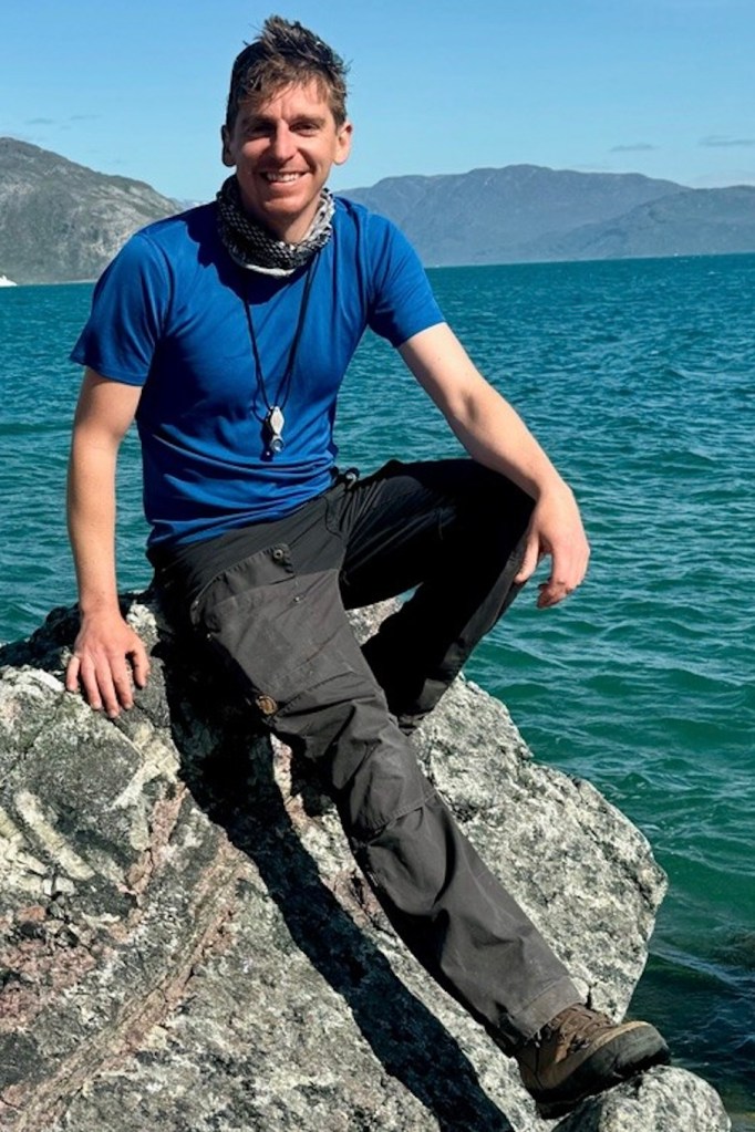A photo of Owen Weller sitting on a rock in southern Greenland.